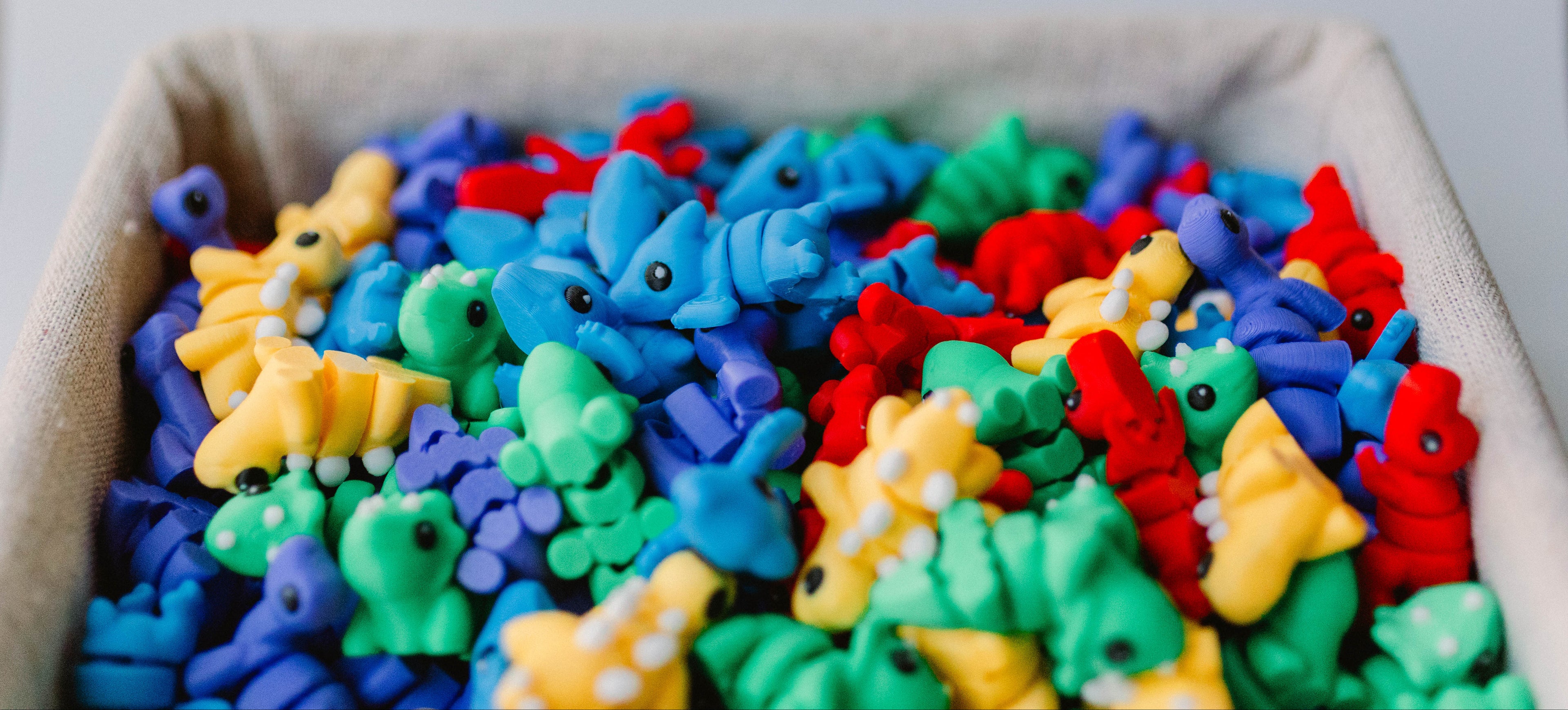 Colorful dinosaur toys in a box on a light background
